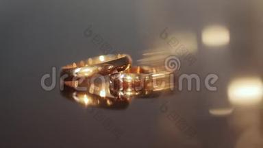 桌子上有两个结婚戒指。 米色背景上的金色订婚戒指。 结婚戒指。 两个华丽的结婚戒指